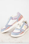 A pair of low-top sneakers in a pastel colorway featuring light blue suede, white leather panels, lavender purple overlays, and beige and red wavy stripe accents. One shoe is positioned upright and the other lies on its side, showcasing the side profile with a gold monogram logo on a clean, light marble surface against a white background.