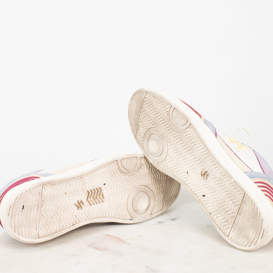 A pair of low-top sneakers shown from the sole side, resting on a light marble surface against a white background.