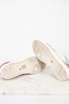A pair of low-top sneakers shown from the sole side, resting on a light marble surface against a white background.