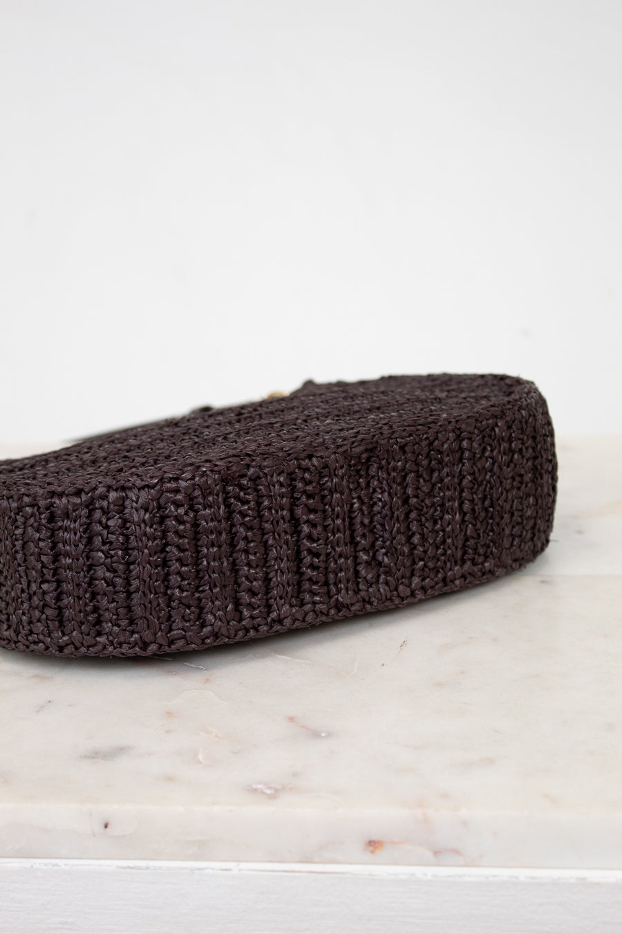 Brown woven purse on a marble and light gray background