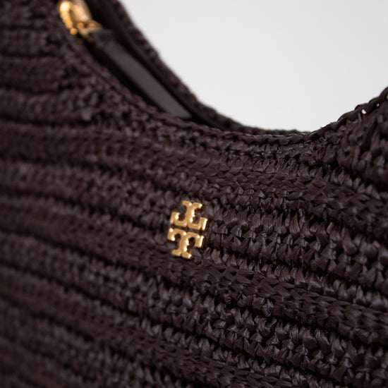 Close-up of a textured brown handbag with a gold logo on a light gray background