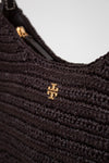 Close-up of a textured brown handbag with a gold logo on a light gray background
