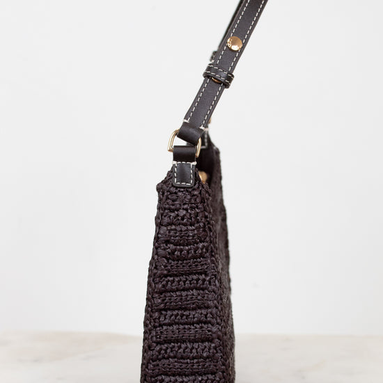 Brown crochet handbag with leather strap on a light gray background