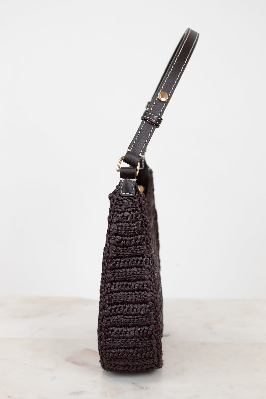 Brown crochet handbag with leather strap on a light gray background