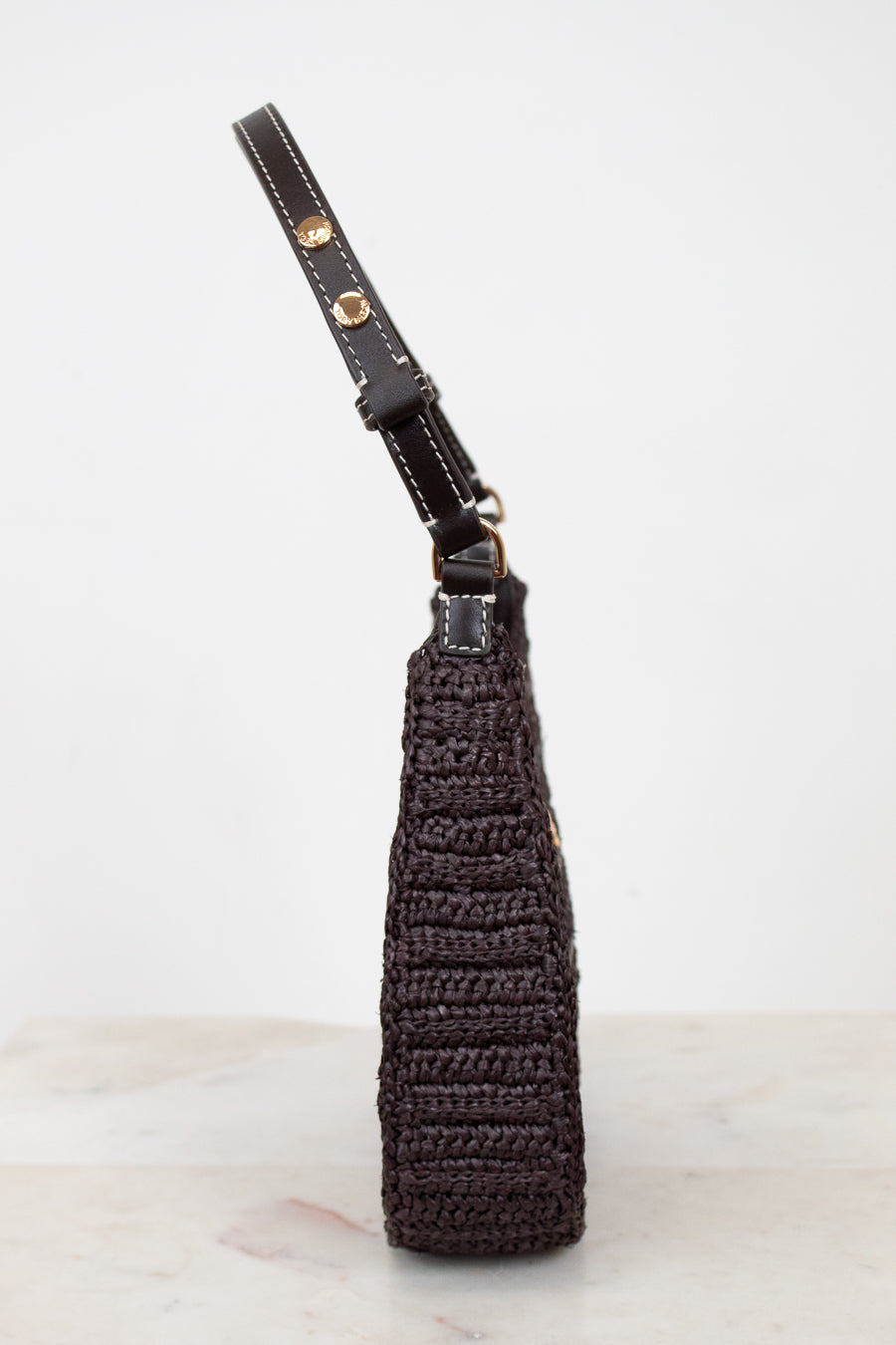 Brown woven purse with brown strap on a light gray background