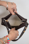 Person holding brown woven purse with dark brown leather straps open showing clean interior