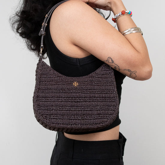 Person wearing a textured brown handbag against a plain background