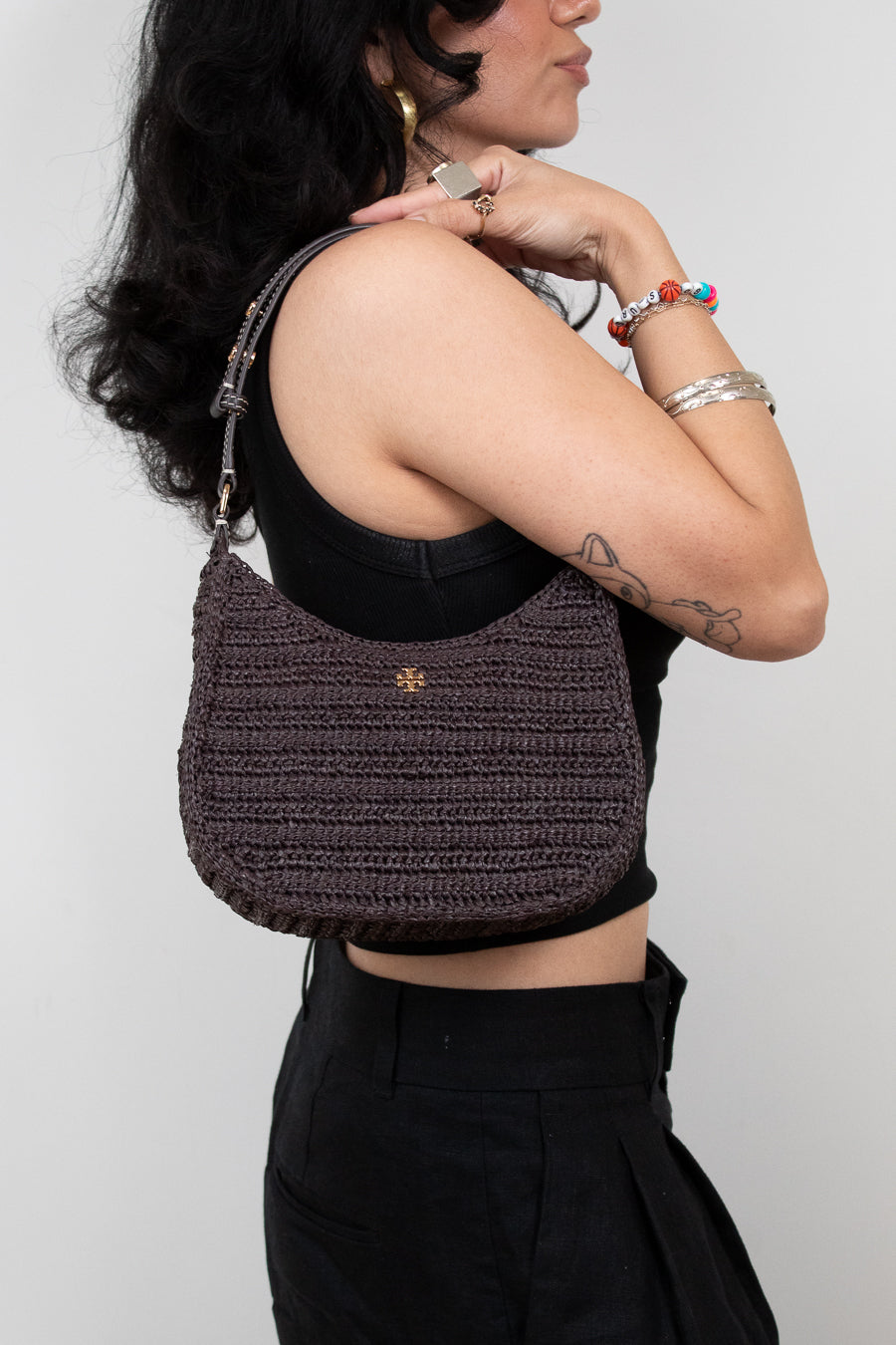 Person wearing a textured brown handbag against a plain background