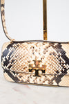 A close-up of a handbag with beige, black, and brown snakeskin leather, featuring a gold-tone metal logo clasp on the front flap.
