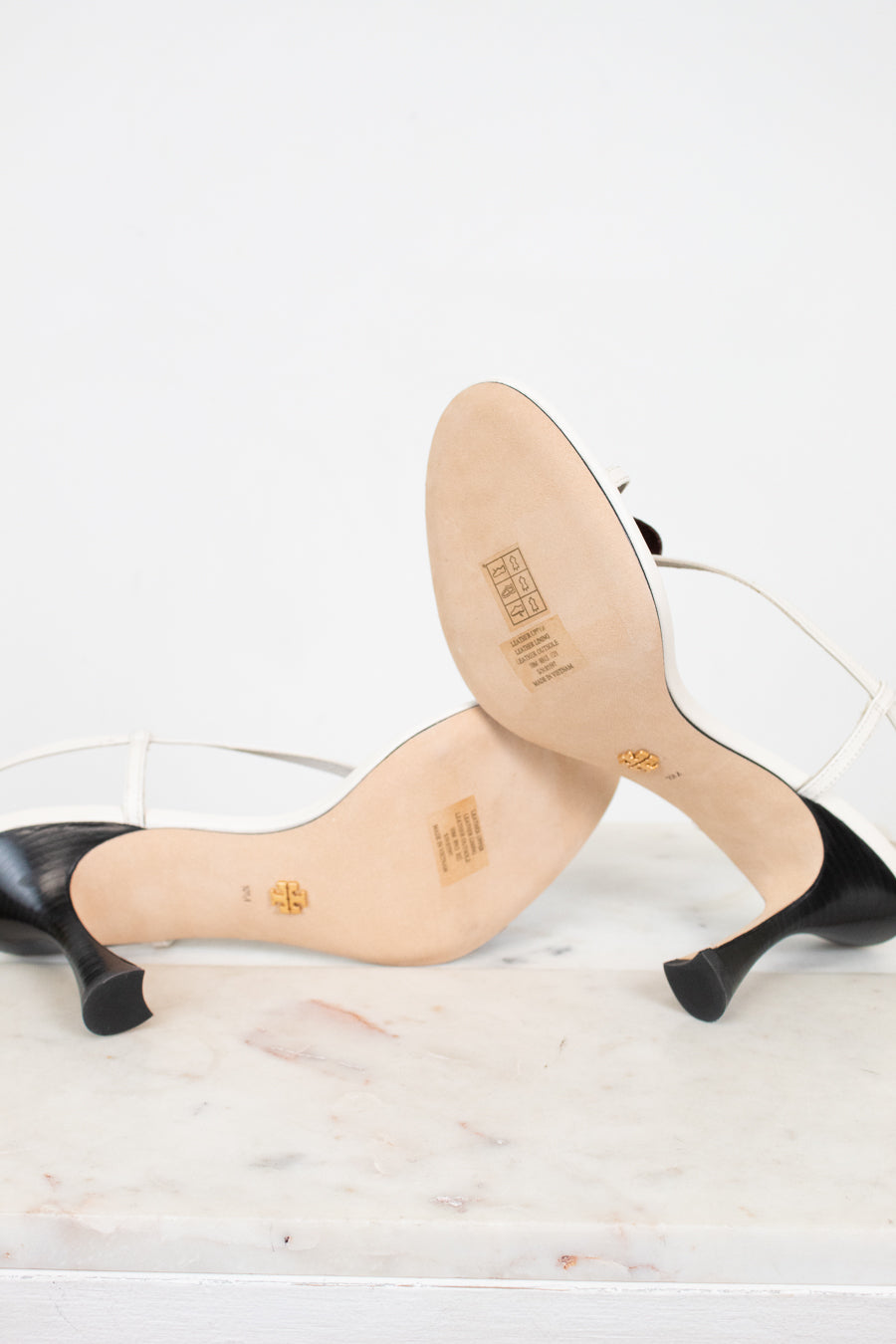 Bottom view of high-heeled shoes with beige soles on a white background