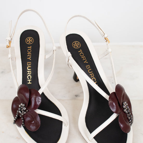 Tory Burch sandals with floral embellishments on a marble surface