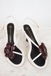 Tory Burch sandals with floral embellishments on a marble surface