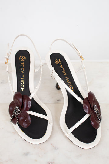 Tory Burch sandals with floral embellishments on a marble surface