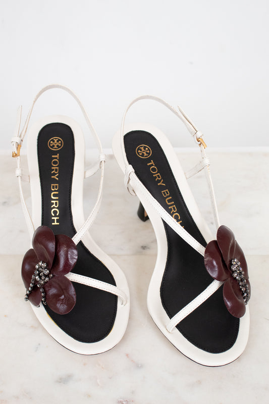 Tory Burch sandals with floral embellishments on a marble surface