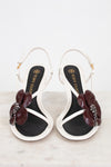 Pair of black and white sandals with floral embellishments on a light background
