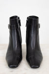 View from the front of black smooth leather ankle boots with ankle strap detail