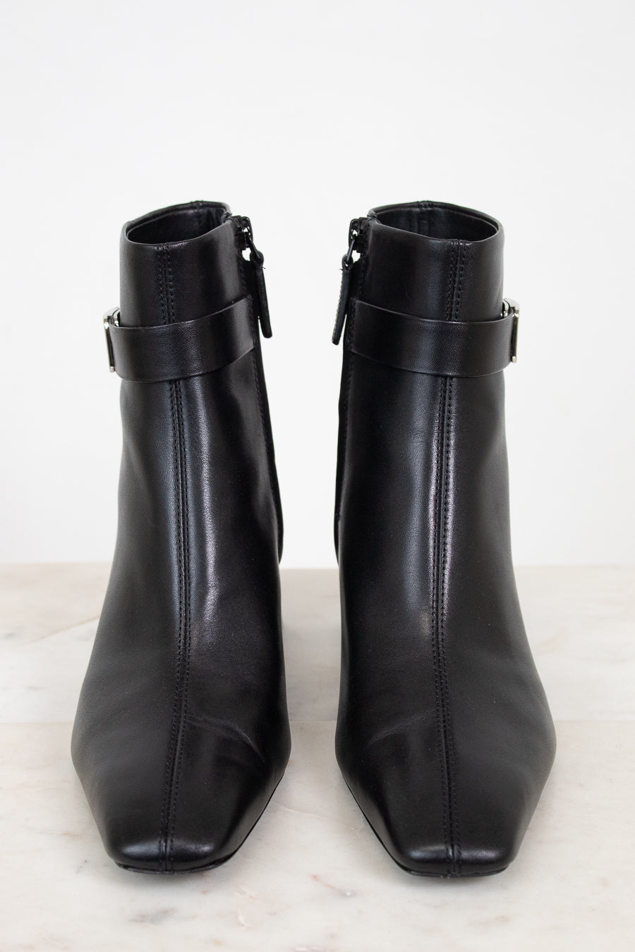 View from the front of black smooth leather ankle boots with ankle strap detail