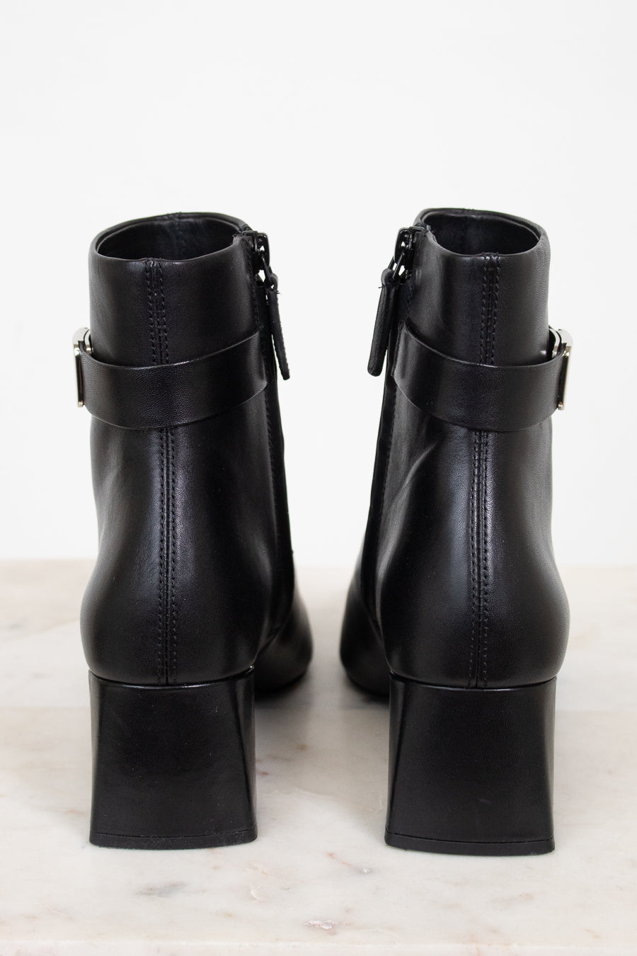 Back view of black leather ankle boots showing block heel and ankle strap detail