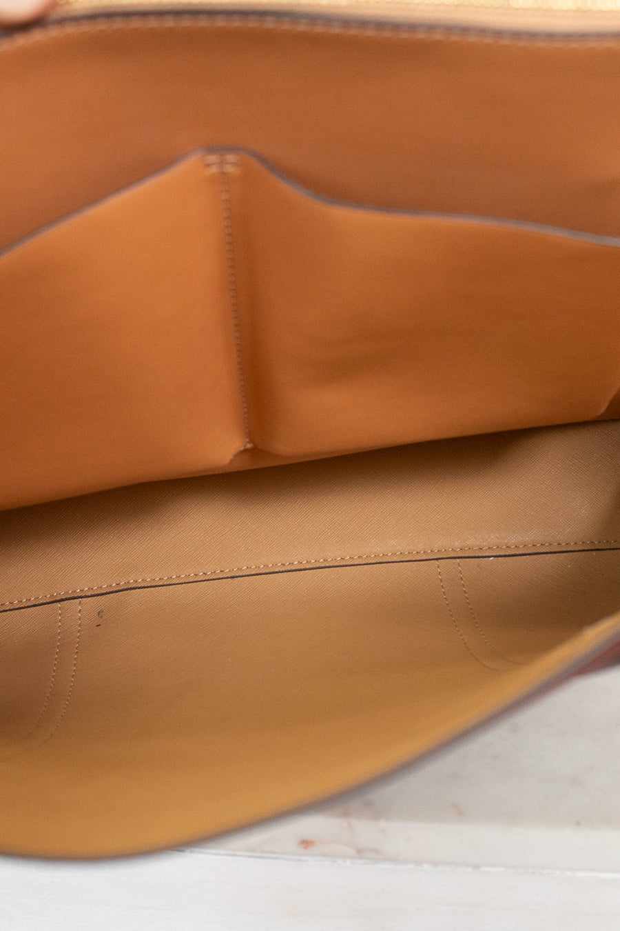 Close-up of the tan leather interior lining of a handbag, showing the smooth material and fine stitching.