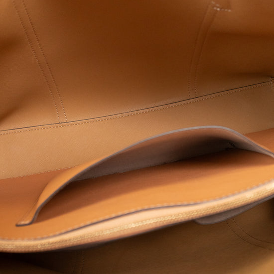 Close-up of the interior of a tan leather bag, showing stitched compartments and a small red leather strap detail at the top and bottom edges.