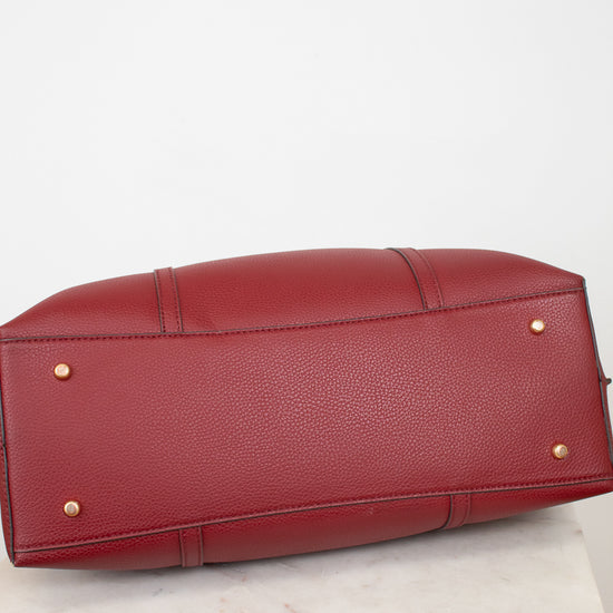 A red pebbled leather handbag shown from the bottom, resting on a white marble surface against a white background.