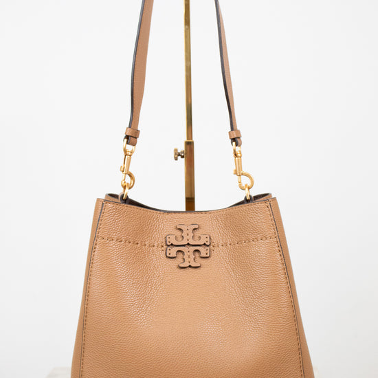 Tan handbag with gold accents on a white background