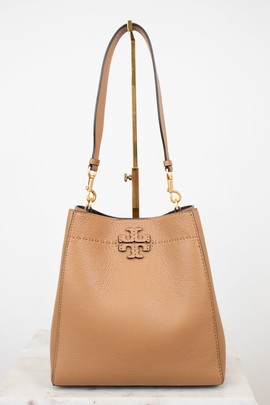 Tan handbag with gold accents on a white background