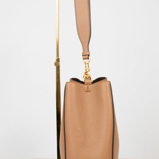 Tan handbag with a gold handle on a white background