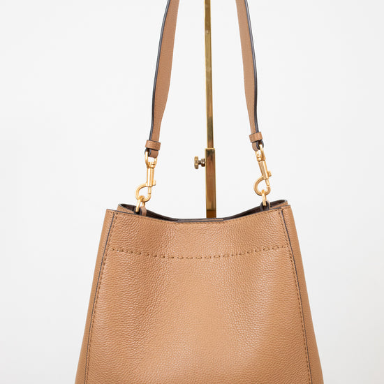 Tan handbag with gold accents on a white background