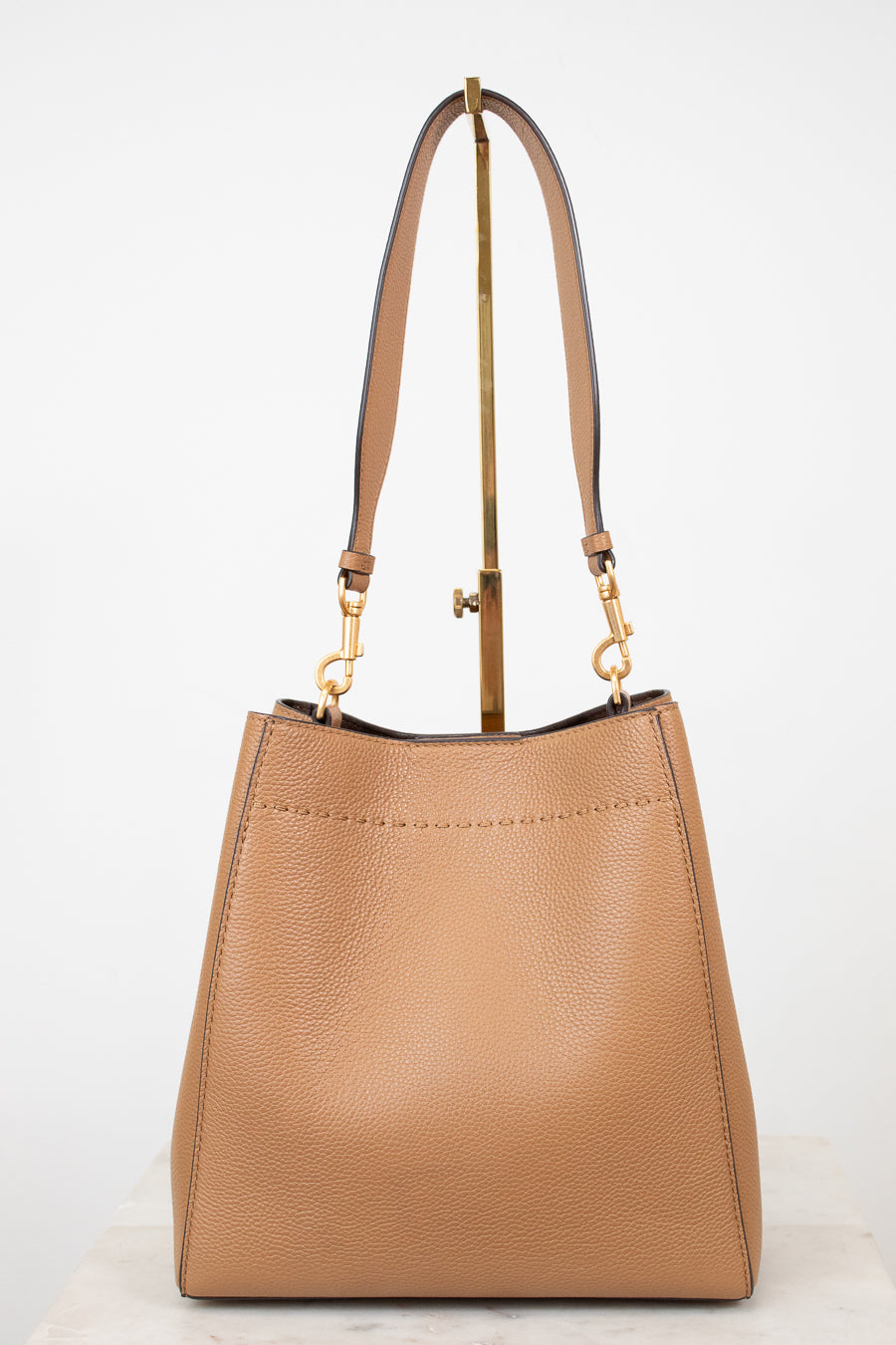 Tan handbag with gold accents on a white background