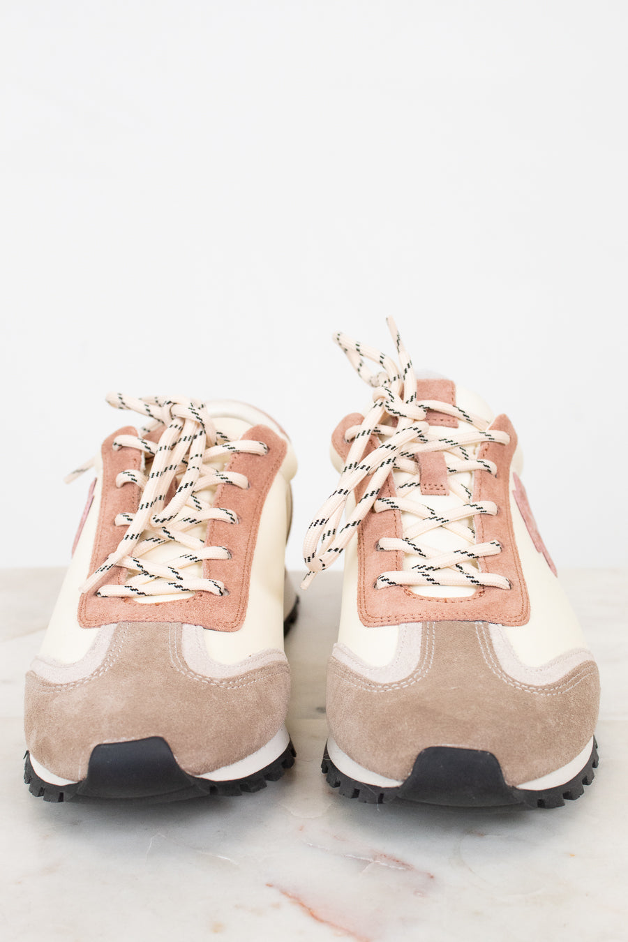 Pair of beige and pink high-top sneakers on a light background