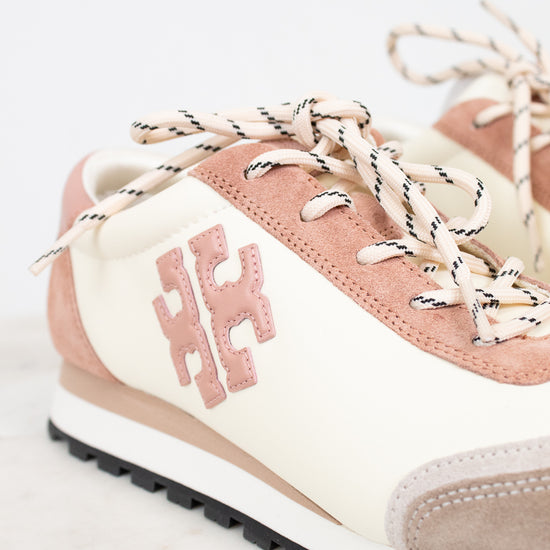 Pink and beige sneaker with white laces on a light gray background