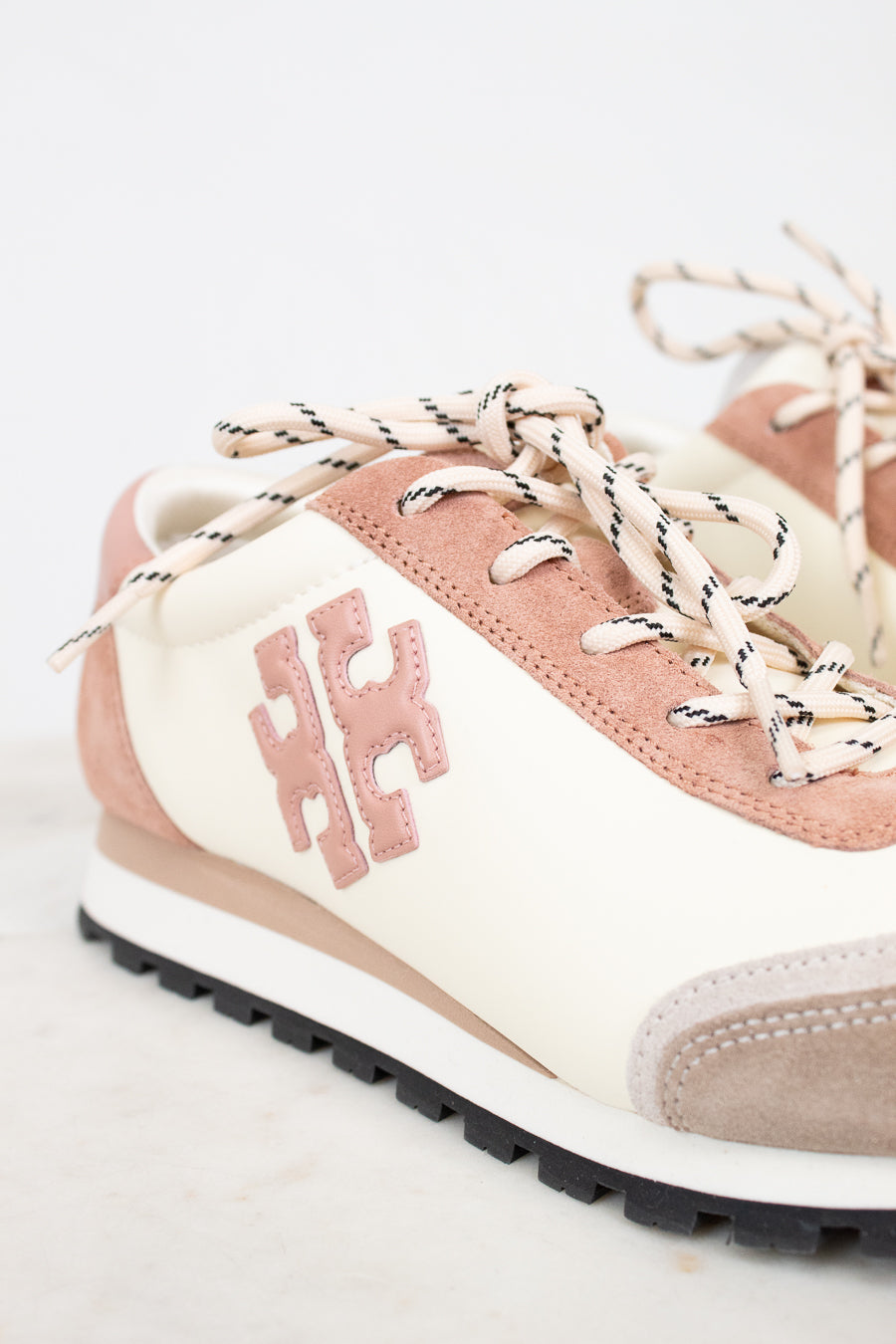 Pink and beige sneaker with white laces on a light gray background