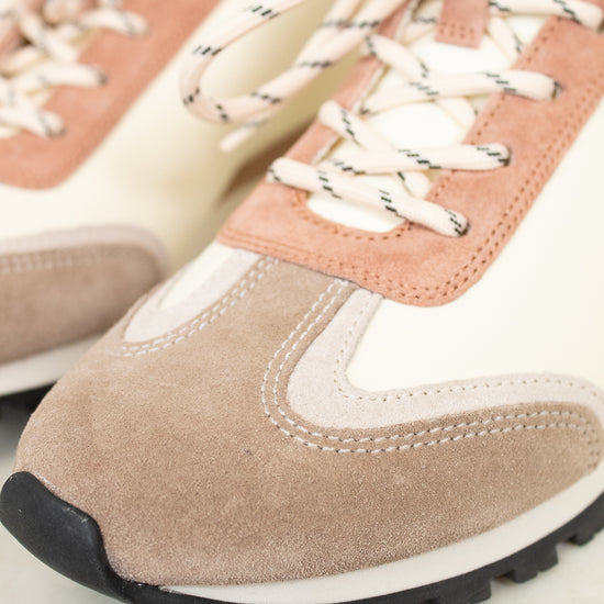 Close-up of a pair of sneakers with pink and beige accents on a light background