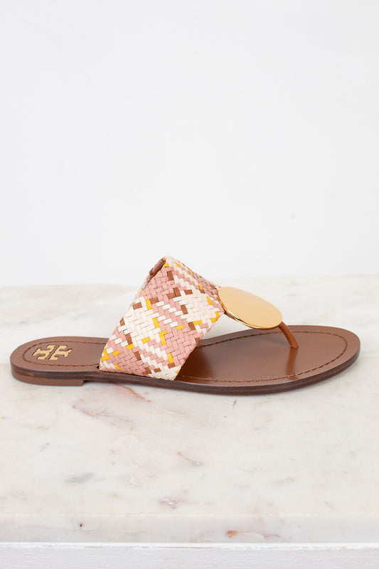 Flip-flop sandal with woven strap and gold buckle detail on a marble surface