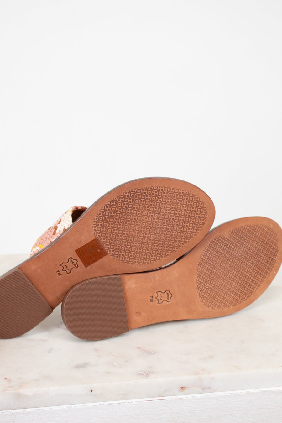 Close-up of brown shoe soles on a white surface