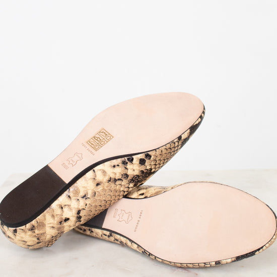 A pair of women's slide sandals shown from the bottom, featuring a beige and black snakeskin patterned sole and a light pink leather insole with embossed branding.