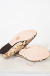 A pair of women's slide sandals shown from the bottom, featuring a beige and black snakeskin patterned sole and a light pink leather insole with embossed branding.