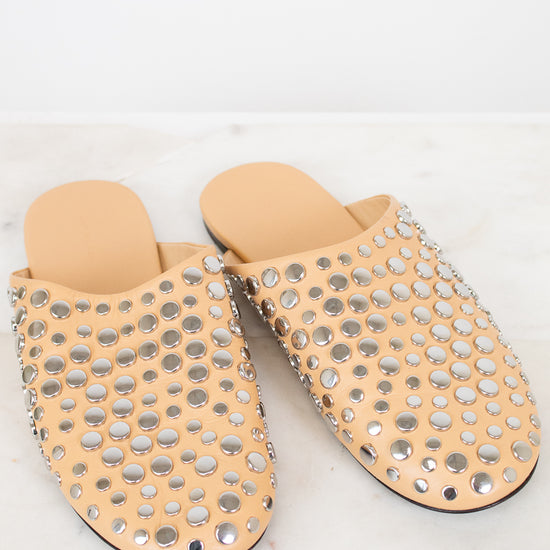 Pair of beige slippers with silver stud details on a light background