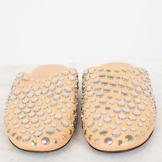 Pair of beige slippers with silver studs on a white background