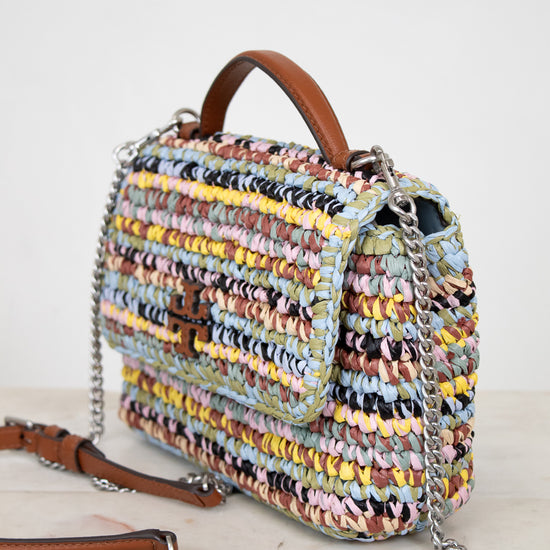 Multicolored woven handbag with a brown Tory Burch logo and chain detail on a light background