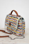 Multicolored woven handbag with a brown Tory Burch logo and chain detail on a light background