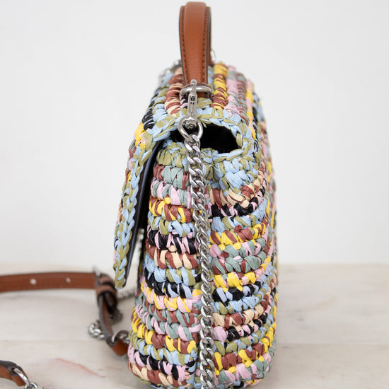 Multicolored woven handbag with a chain detail on a white background