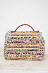 Multicolored woven handbag with a brown handle on a light background