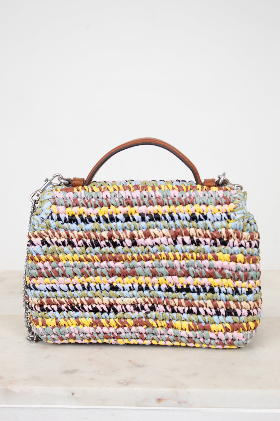 Multicolored woven handbag with a brown handle on a light background