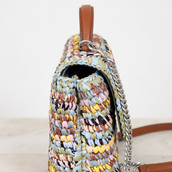 Multicolored woven handbag with a chain detail on a light background