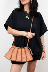 Woman holding a brown leather handbag against a white background