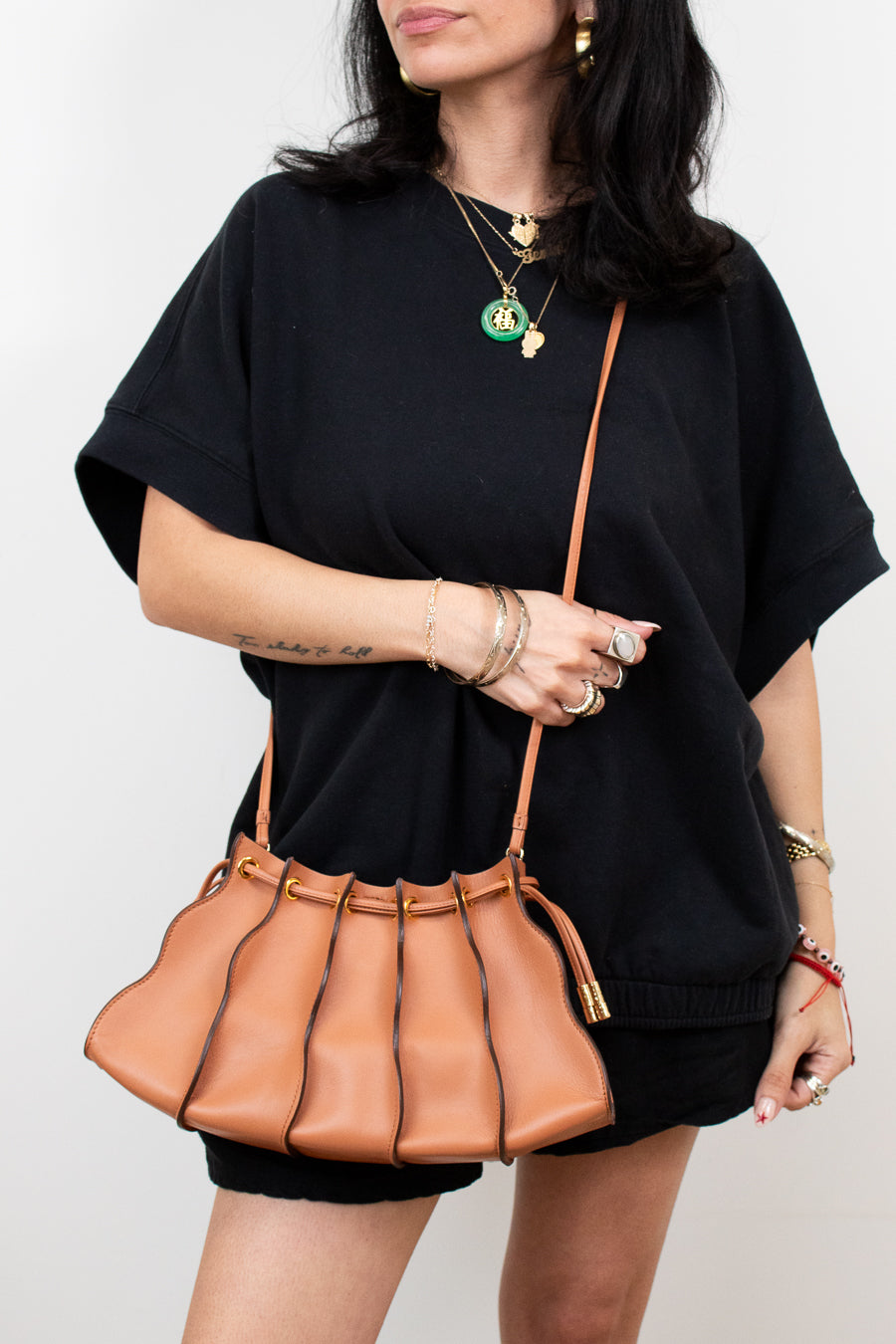 Woman holding a brown leather handbag against a white background