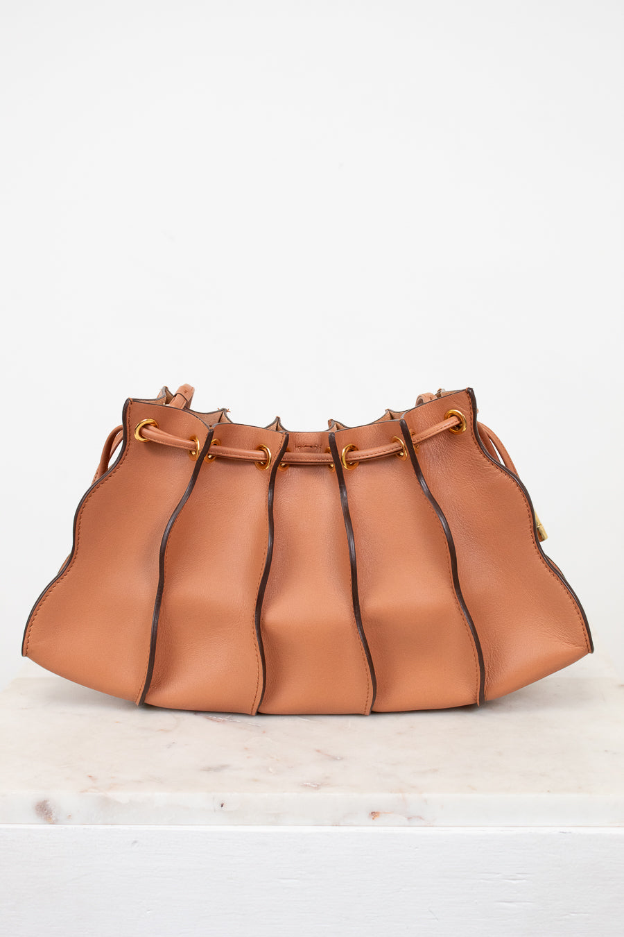 Brown leather handbag with drawstring on a white background
