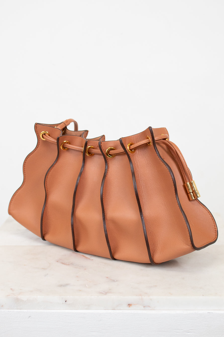 Tan leather handbag with drawstring on a light background